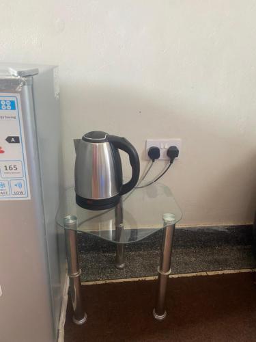 a tea kettle on a glass table next to an electrical outlet at Kabale studio apartments in Kabale