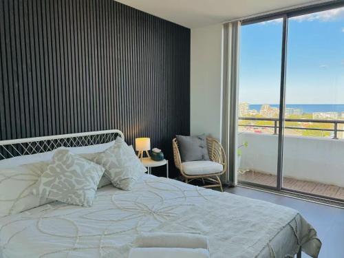a bedroom with a bed and a large window at CBD Penthouse Retreat - Stunning Ocean & City View in Wollongong
