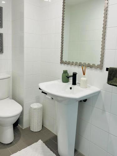 a white bathroom with a sink and a toilet at CBD Penthouse Retreat - Stunning Ocean & City View in Wollongong