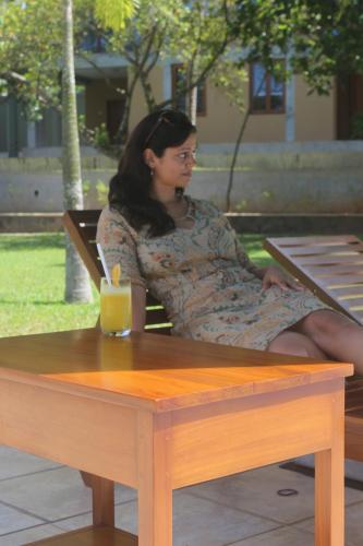 a woman sitting on a bench at a table at Ensenada Bolgoda in Piliyandala
