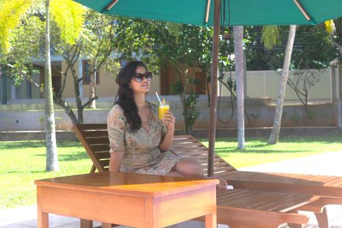 a woman sitting on a bench with a drink at Ensenada Bolgoda in Piliyandala