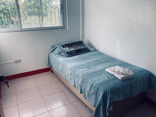 uma pequena cama em um quarto com janela em The poolhouse at McKirdy's mango farm em Sison