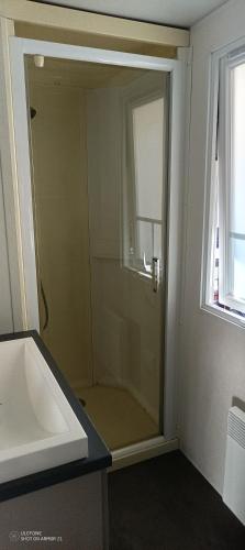 une salle de bain avec une douche et un lavabo et une fenêtre dans l'établissement Mobil Home La Palmyre, aux Mathes