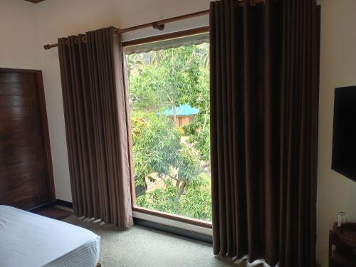a bedroom with a window with a view of a tree at World's End Base Eco-Village in Belihul Oya