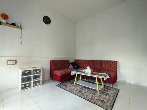 a living room with a red couch and a table at Rumah Liburan Sikabu-kabu in Airtabit