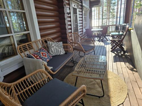 a porch with wicker chairs and a bench and tables at Vernetti 1 Koli in Kolinkylä