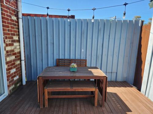 un tavolo e una panca di legno con una pianta in vaso su un ponte di Port Adelaide getaway a Port Adelaide