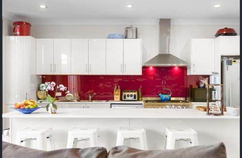 una cucina con mobili bianchi e una parete rossa di Port Adelaide getaway a Port Adelaide