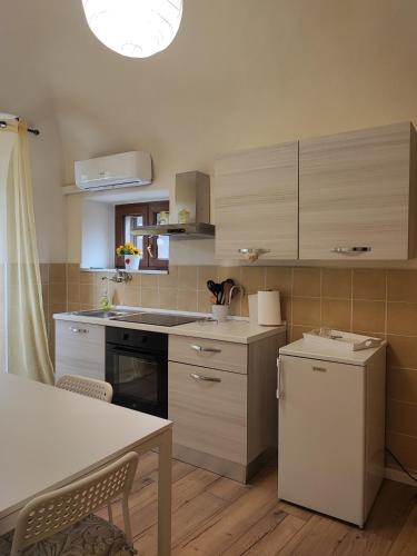 a kitchen with white cabinets and a table with chairs at La casina nel borgo in Volterra