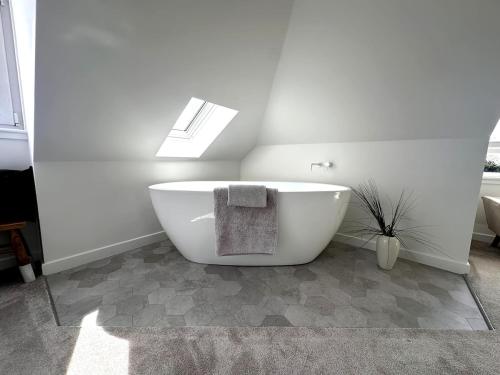 a bathroom with a large white bath tub with a window at Kaimes Kip Stylish Edinburgh Five Bedroom Home in Edinburgh