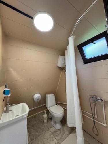 a bathroom with a toilet and a sink and a window at Cottages in Chirdili in Chirdili
