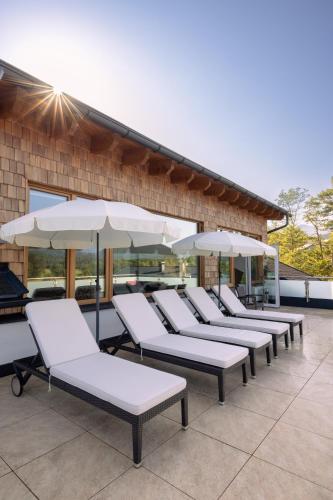 a row of lounge chairs and umbrellas on a patio at R&R Residenzen Ferienwohnungen in Mitterbach
