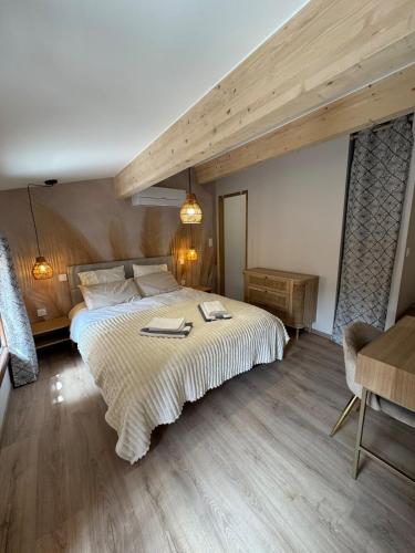 a bedroom with a large bed and a wooden floor at Gîte plein de charme avec ses poutres apparentes , ses pierres et son jacuzzi extérieur in Caux