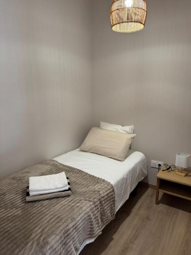 a bedroom with a bed with white sheets and a lamp at Gîte plein de charme avec ses poutres apparentes , ses pierres et son jacuzzi extérieur in Caux