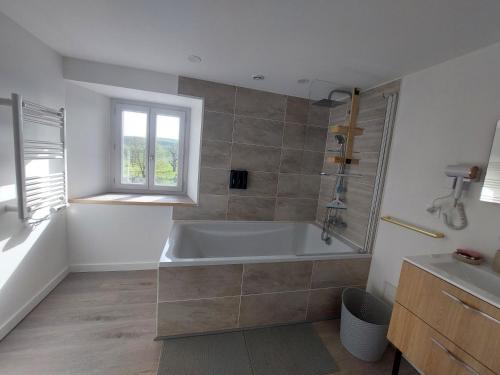 a white bathroom with a tub and a window at O Gîte d'anthony in Talizat