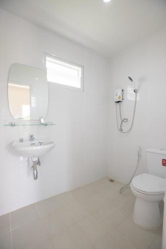 a white bathroom with a toilet and a sink at Praew Place Phimai in Ban Muang