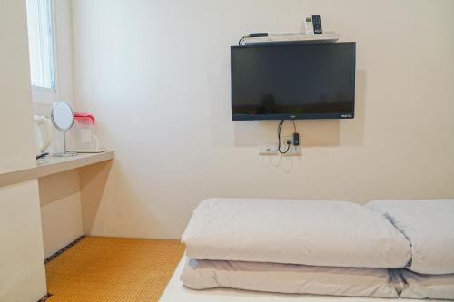 a white room with a flat screen tv on the wall at The Wind BnB Ⅱ in Budai