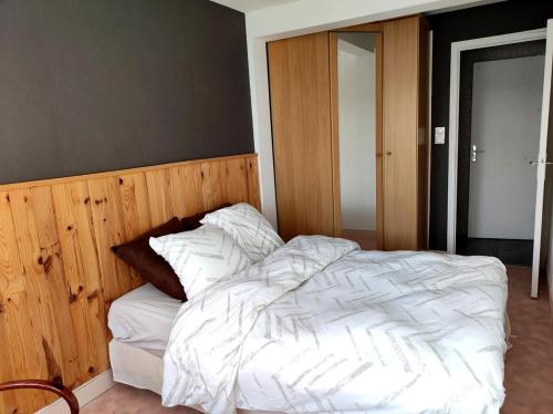 a bedroom with a white bed with a wooden headboard at Logement autonome pour 2 personnes au RDC in Guéret