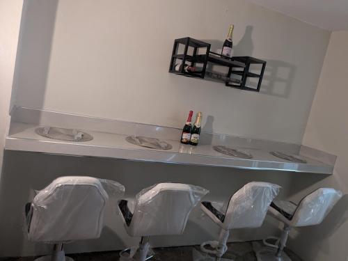 a bar with three chairs under a counter with bottles of wine at BridgeView Arcadia One in Portmore