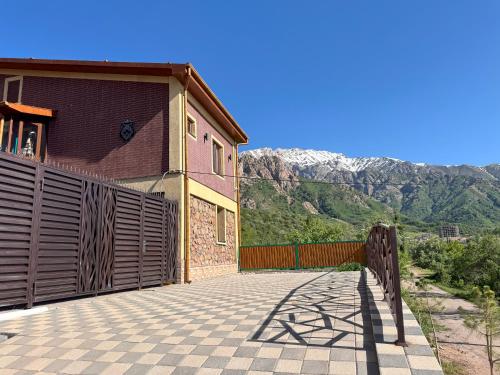 a building with a fence and mountains in the background at Mountain paradise Премиум дача в Чимгане in Chimgan