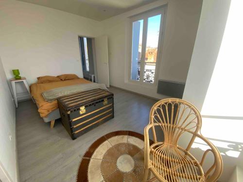 une chambre avec un lit, une chaise et une fenêtre dans l'établissement appartement en plein centre ville, à Sète