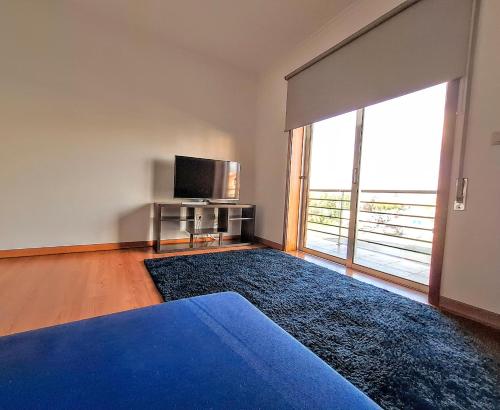 a bedroom with a blue bed and a television at Aveiro Atlantic House in Ílhavo