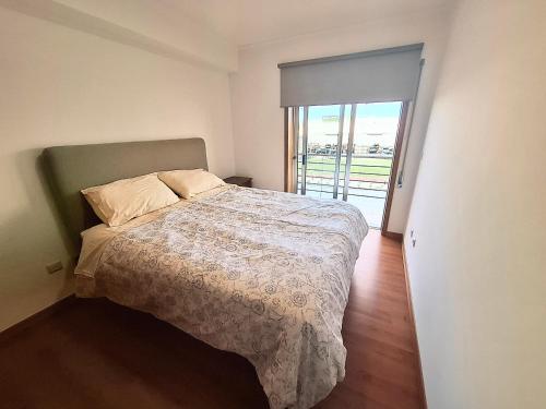 a bedroom with a bed and a door to a balcony at Aveiro Atlantic House in Ílhavo