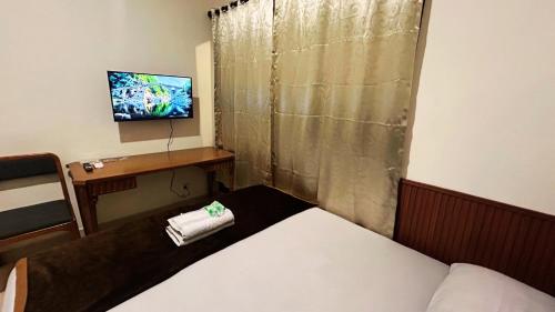 a room with a bed and a desk with a television at The Segaran House ONLY Syariah Unmarried Couple Not Allowed in Jakarta