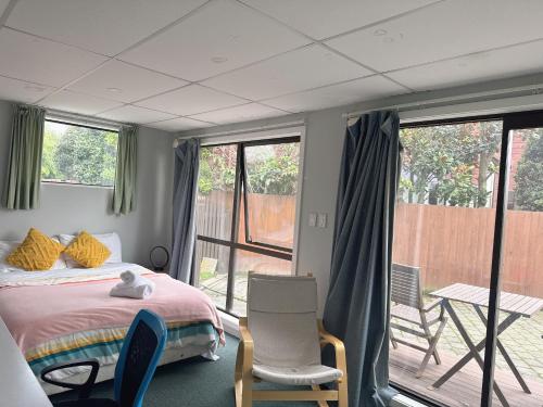 a bedroom with a bed and chairs and a balcony at West Lake one bedroom accommodation in Christchurch
