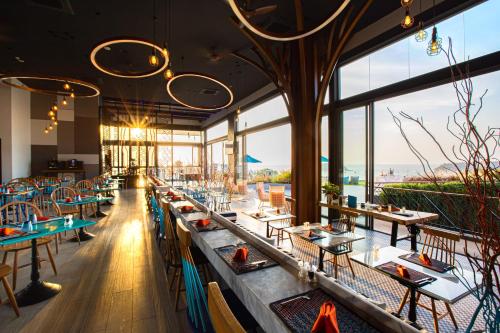a restaurant with tables and chairs and large windows at The SIS Kata Resort - Adult Only in Kata Beach