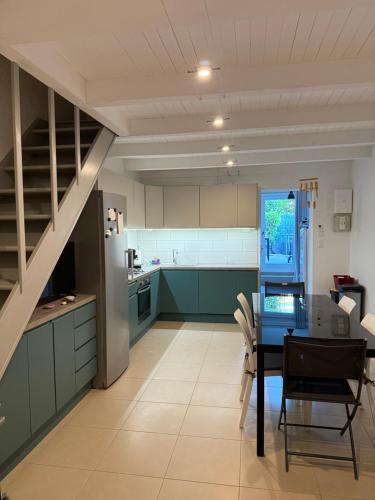 une cuisine avec des placards verts, une table et un escalier dans l'établissement Maison a la plage, à Poggio-Mezzana