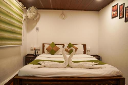 two swans made out of towels sitting on a bed at Ela Ecoland Nature Retreat in Munnar