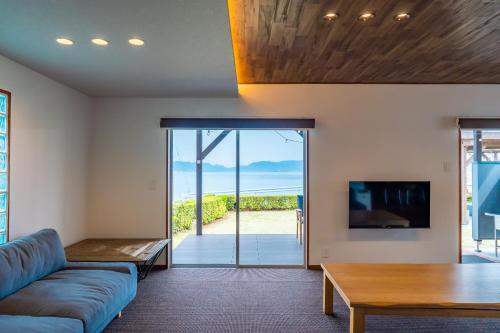 ein Wohnzimmer mit einer Couch, einem Fernseher und einem Tisch in der Unterkunft Seaside Villa KAMANO in Aji