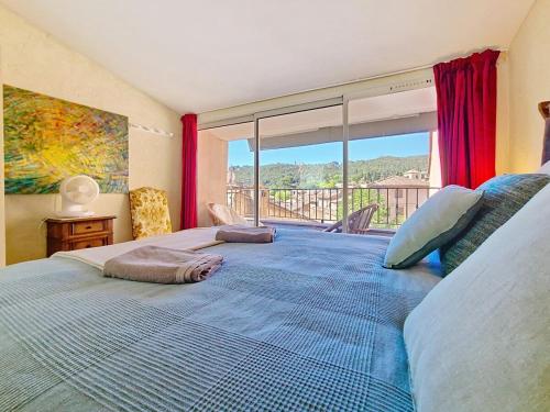 une chambre avec un grand lit avec une grande fenêtre dans l'établissement En plein cœur du village , Terrasse avec vue, à Cotignac
