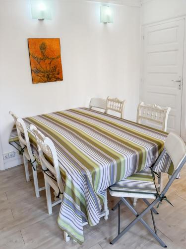 a dining room table with chairs and a striped table cloth at La maison des Hortensias Vic-Sur-Cère, 10 pers in Vic-sur-Cère