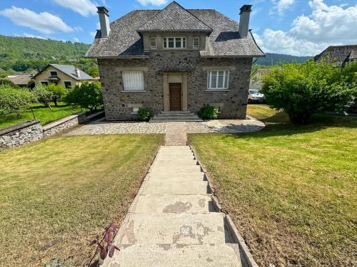 a stone house with a pathway leading to the front door at La maison des Hortensias Vic-Sur-Cère, 10 pers in Vic-sur-Cère