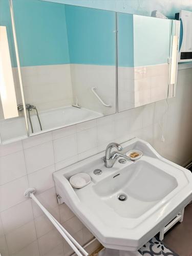 a white bathroom with a sink and a mirror at La maison des Hortensias Vic-Sur-Cère, 10 pers in Vic-sur-Cère