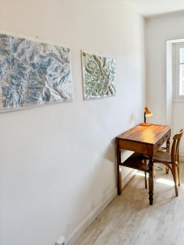 a wooden desk in a room with paintings on the wall at La maison des Hortensias Vic-Sur-Cère, 10 pers in Vic-sur-Cère