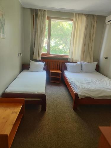 two beds in a room with a window at Хотел Устра in Kŭrdzhali