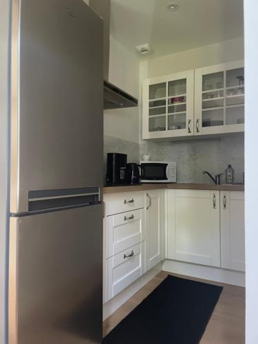  La cuisine est équipée de placards blancs et d'un réfrigérateur. dans l'établissement Appartement 4 étoiles dans propriété classée, à Capbreton