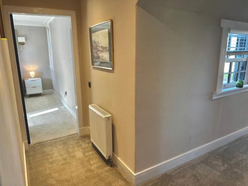 a room with a hallway with a mirror and a radiator at Red Roofs - 5BR Luxury - Large Gardens - EV Point - Near Edinburgh in Newtongrange