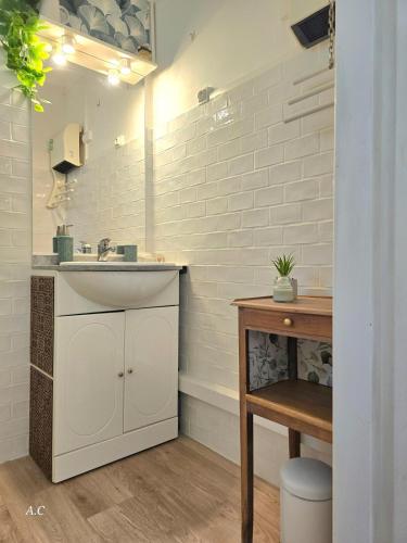 La salle de bains blanche est pourvue d'un lavabo et d'une table. dans l'établissement La Chambre Sous Les Oliviers - Très cocooning avec grand jardin, borne recharge électrique, à 5min du centre - BY AURAconciergerie, à La Cadière-dʼAzur