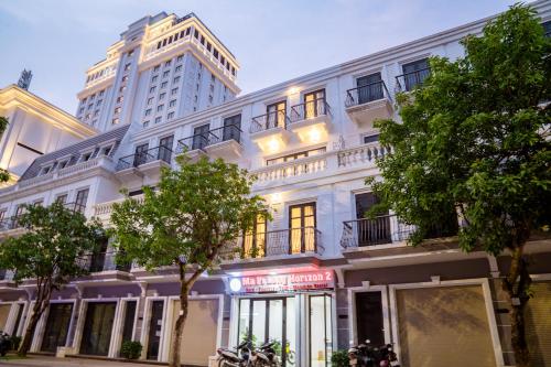 a white building on a street with a tall building at Mapileng Horizon 2 - Hotel - Tour - BusTicket - Motobike Rent in Ha Giang
