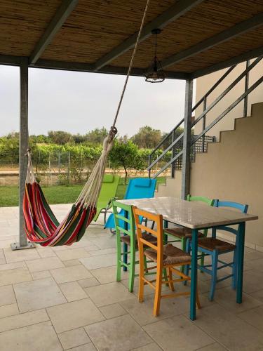 a patio with a table and chairs and a hammock at le casette in Aradeo
