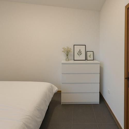 a bedroom with a white bed and a dresser at Cosy studio Midi station in Brussels