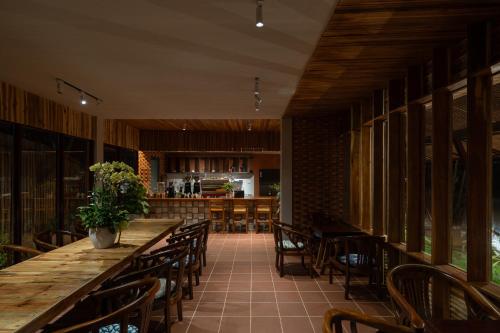 a restaurant with a long wooden table and chairs at Chuồn Chuồn Retreat in Phan Thiet