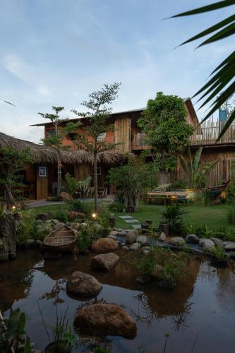 a garden with a pond in front of a building at Chuồn Chuồn Retreat in Phan Thiet