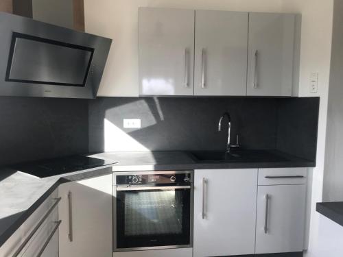 une cuisine avec des armoires blanches, un évier et une cuisinière dans l'établissement La landaise, à Biscarrosse