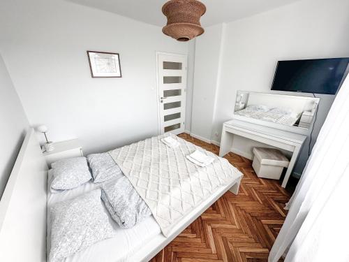 a white bedroom with a bed and a desk at Apartament przy Rynku in Sandomierz
