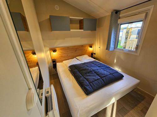 Cette petite chambre comprend un lit avec une couverture bleue. dans l'établissement Camping Les Goélands Carnac, à Plouharnel